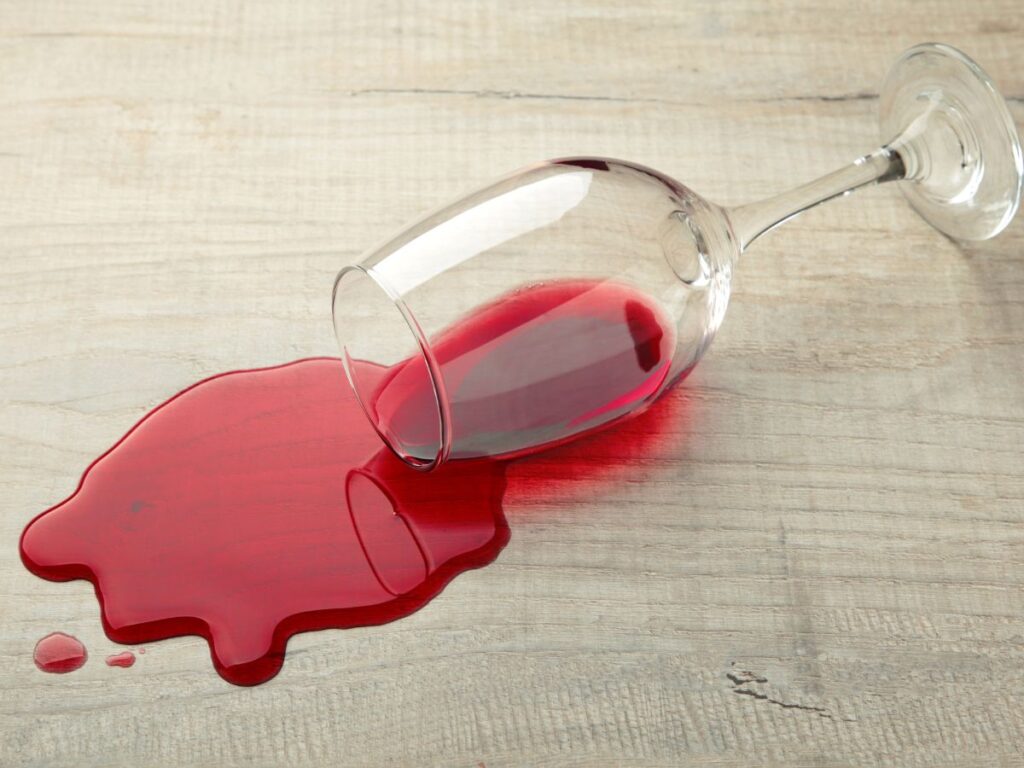 glass of red wine spilled on timber floor